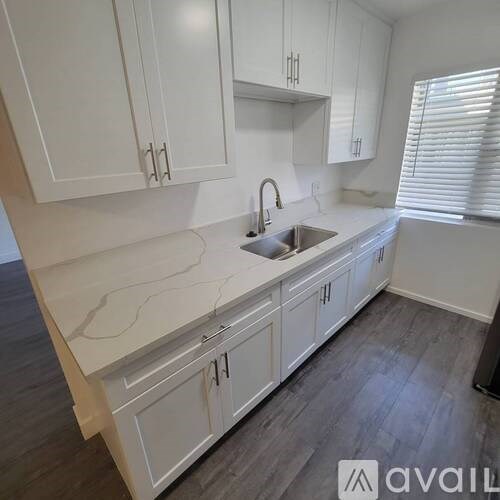 A kitchen with white cabinets and a marble countertop.