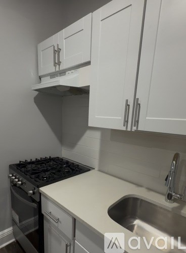 A kitchen with white cabinets and a stove top oven.
