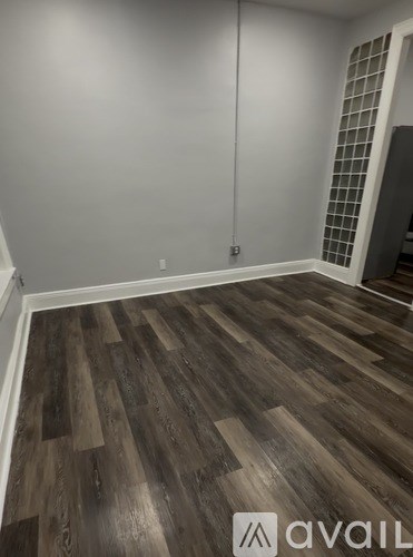 A room with wooden flooring and a wall with a grid pattern.