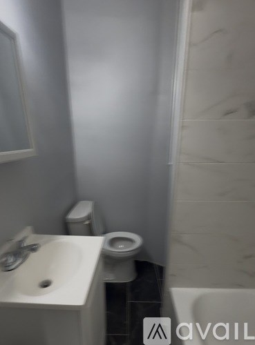 A bathroom with a toilet, sink, and mirror.