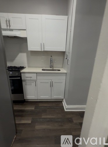A kitchen with white cabinets and a wooden floor.