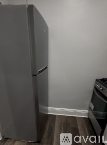 A grey fridge in a kitchen with a wooden floor.