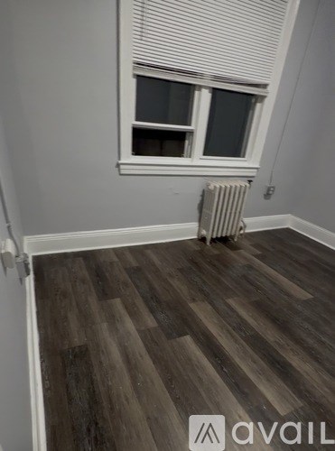 A room with a window and a radiator on the floor.