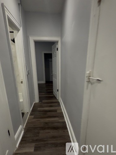 A long hallway with wood floors and white walls.