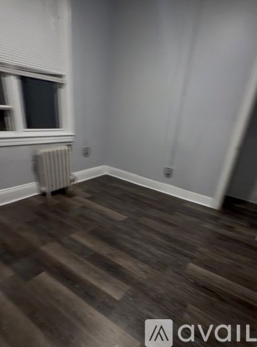 A room with wooden flooring and a window with blinds.
