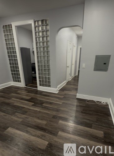 A hallway with a wooden floor and a wall with a shelving unit.