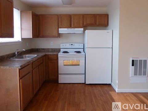 A kitchen with white appliances and wooden cabinets.