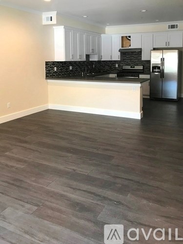 A kitchen with a refrigerator, stove, and cabinets.