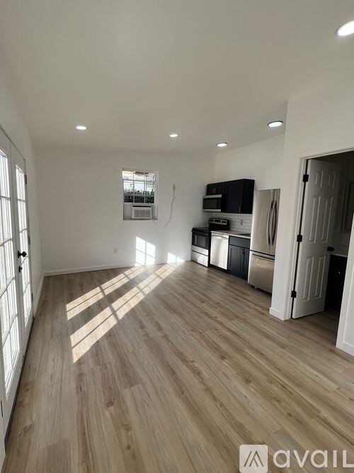 A spacious room with wooden flooring and white walls.