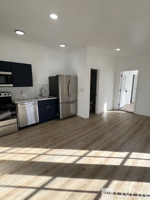 A modern kitchen with wooden floors and stainless steel appliances.