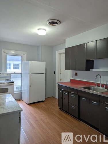 A kitchen with a white refrigerator and black cabinets.