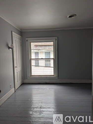 A room with a window and wooden floors.