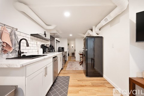 A kitchen with white cabinets and a black fridge.