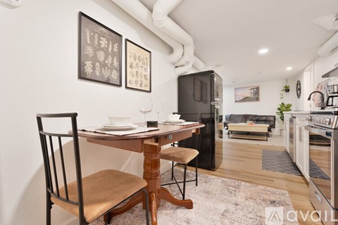 A kitchen with a table and chairs in the foreground and a fridge in the background.