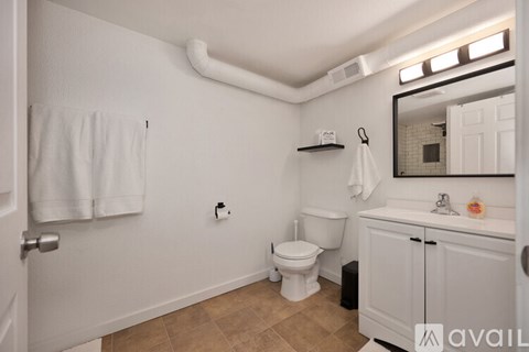A bathroom with a toilet, sink, and mirror.