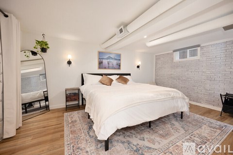 A bedroom with a large bed and a white brick wall.