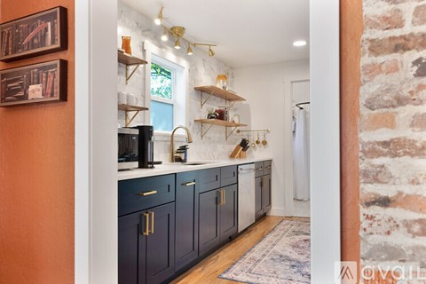 A kitchen with dark blue cabinets and a brick wall.