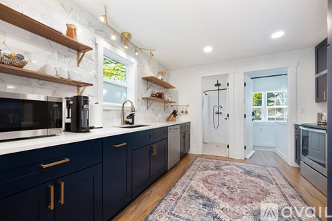 A kitchen with dark blue cabinets and a rug on the floor.