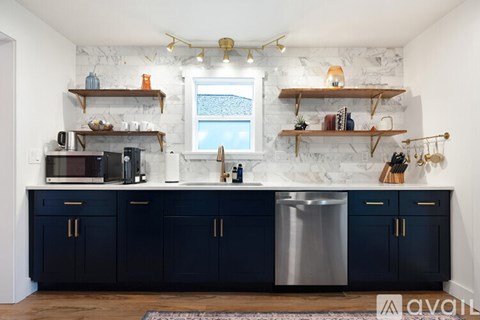 A kitchen with dark blue cabinets and a marble backsplash.