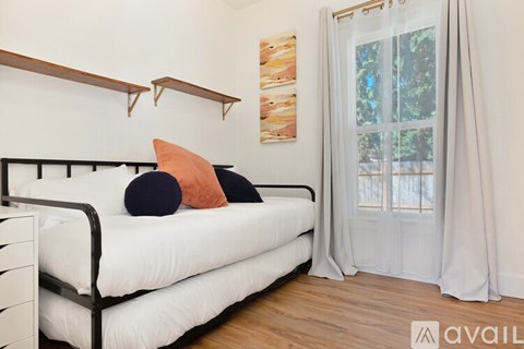 A white couch with two pillows and a painting on the wall.
