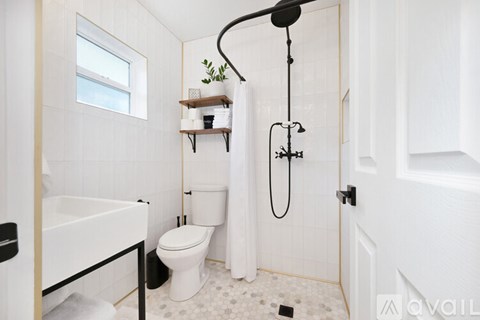 A white bathroom with a toilet, sink, and shower.