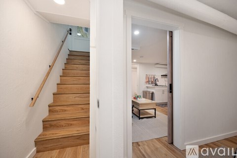 A wooden staircase leads to a brightly lit room with a table and chairs.