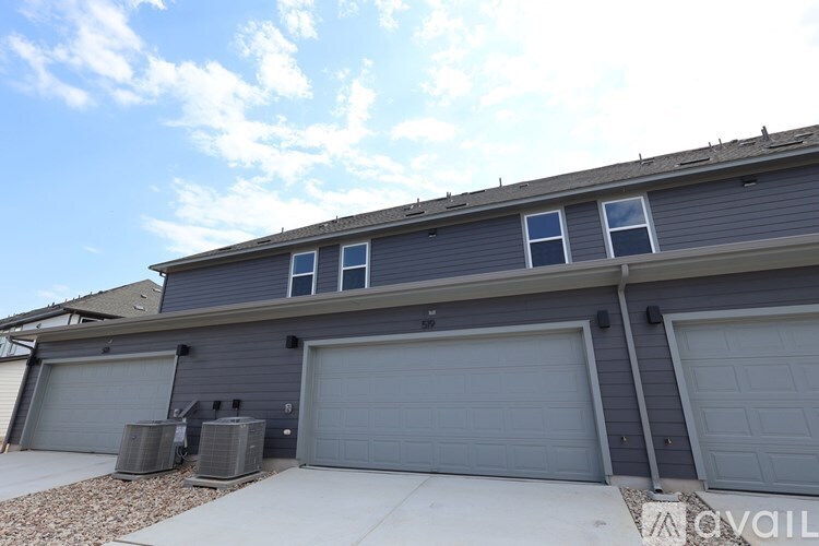 A house with two garages and a roof with a few clouds.