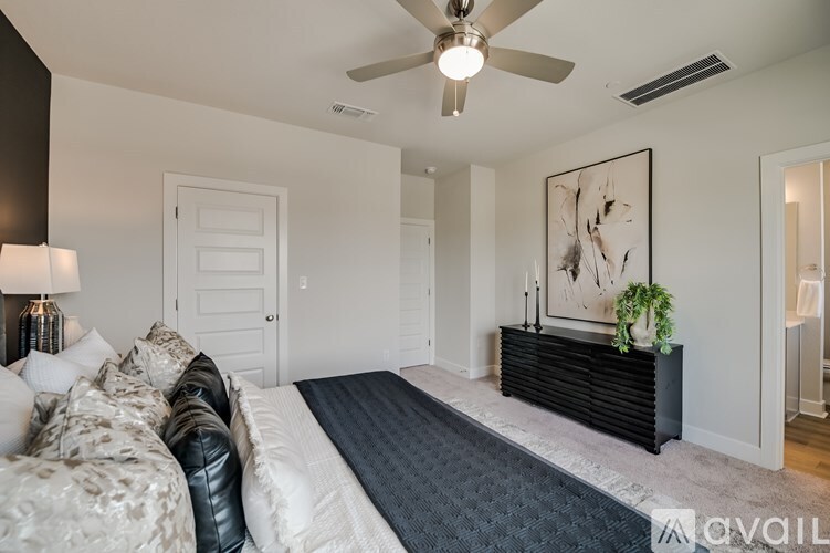 A bedroom with a bed, a bench, and a ceiling fan.