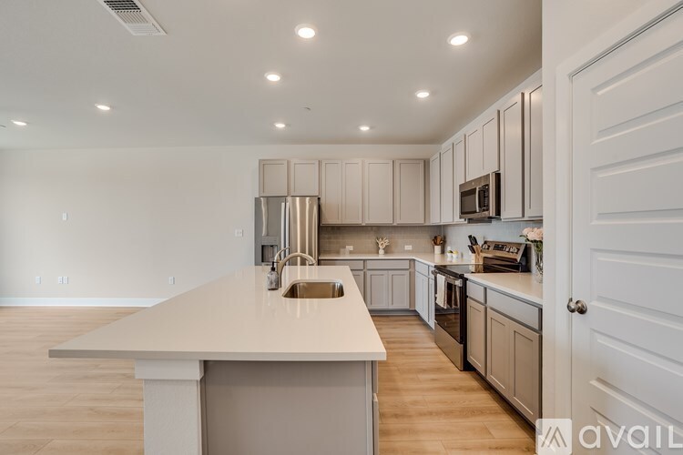 A kitchen with a white countertop and wooden flooring.