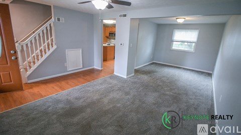 A spacious room with a staircase and a ceiling fan.