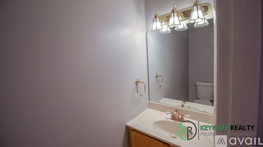 A bathroom with a sink, mirror, and light fixture.