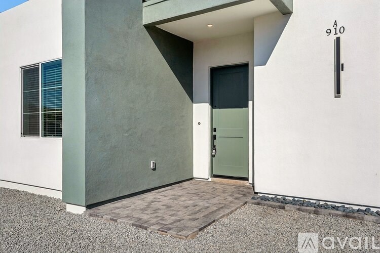 A modern house with a grey door and a window with blinds.