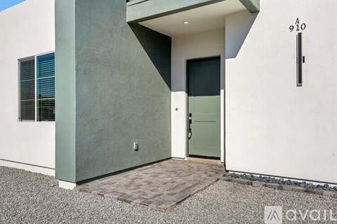 A modern house with a grey door and a window with blinds.
