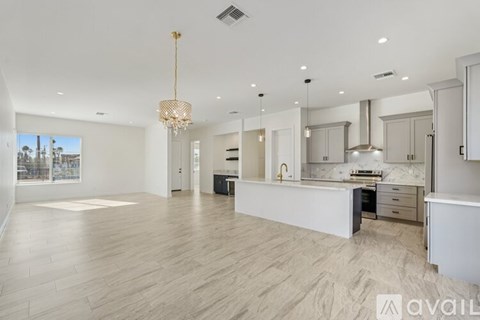 A spacious kitchen and living room with a chandelier and hardwood floors.