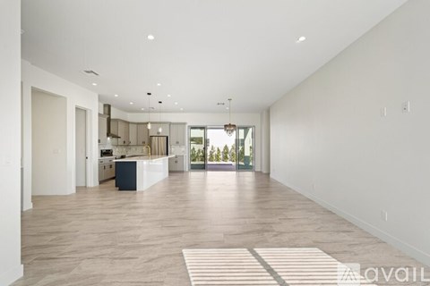 A spacious living room with a kitchen in the background.