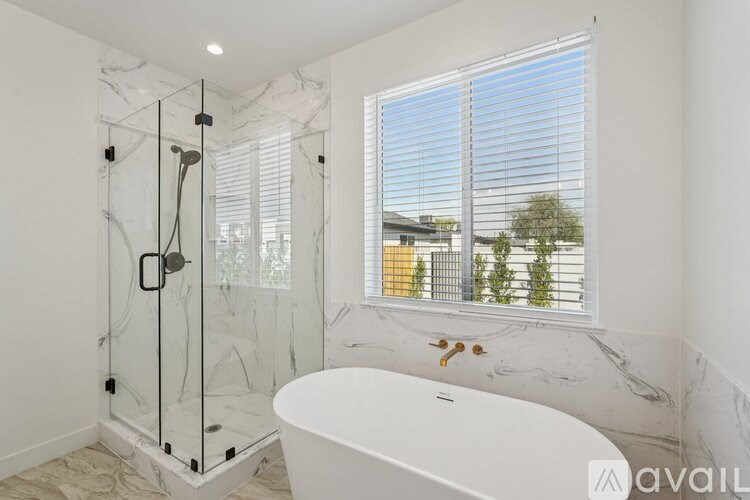 A white bathtub sits in a bathroom with a glass shower stall.