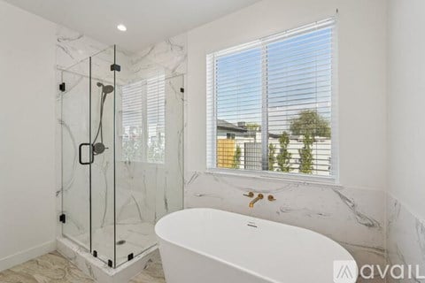 A white bathtub sits in a bathroom with a glass shower stall.