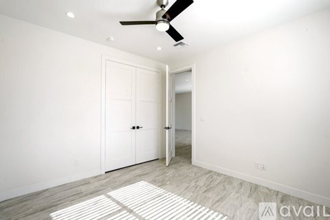 A room with a ceiling fan and two doors.