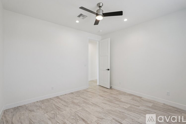 A room with a ceiling fan and a door.