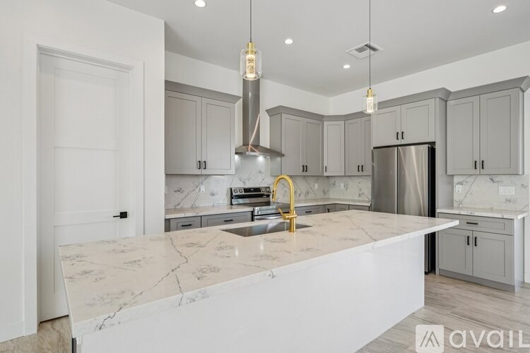 A kitchen with a marble countertop and a stainless steel refrigerator.