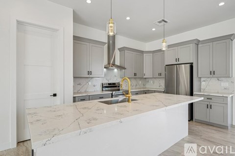 A kitchen with a marble countertop and a stainless steel refrigerator.