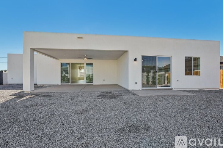 A modern white house with a gravel driveway in front.
