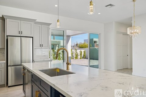 A kitchen with a marble countertop and a stainless steel refrigerator.