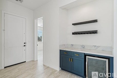 A kitchen with a white door, a marble countertop, and a white wall.