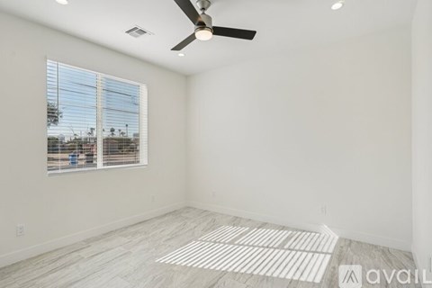 A room with a ceiling fan and a window overlooking a construction site.