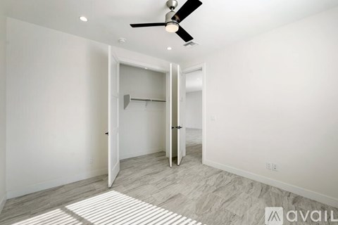 A room with a ceiling fan and a doorway leading to another room.