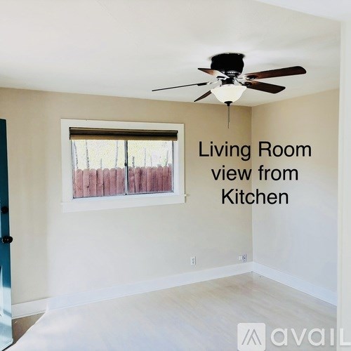 A living room with a ceiling fan and a window.