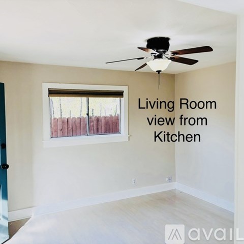 A living room with a ceiling fan and a window.