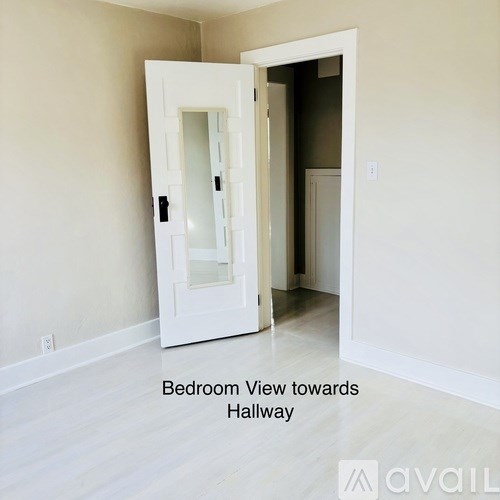 A white door with a glass window is open and leads to a hallway.