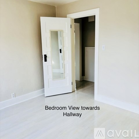 A white door with a glass window is open and leads to a hallway.